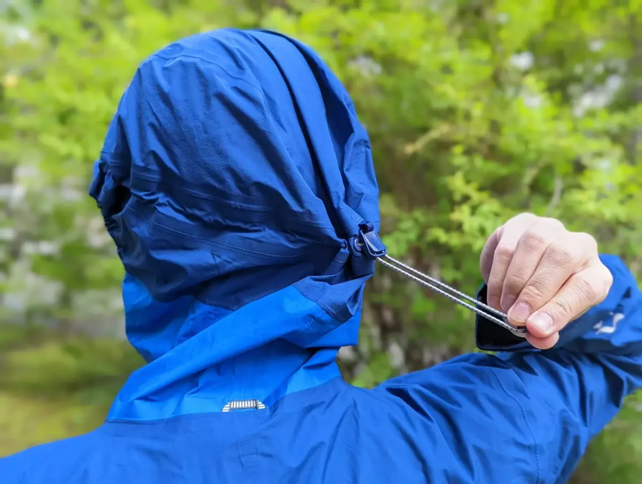 フードはヘルメット対応で、片手でアジャストできるドローコード